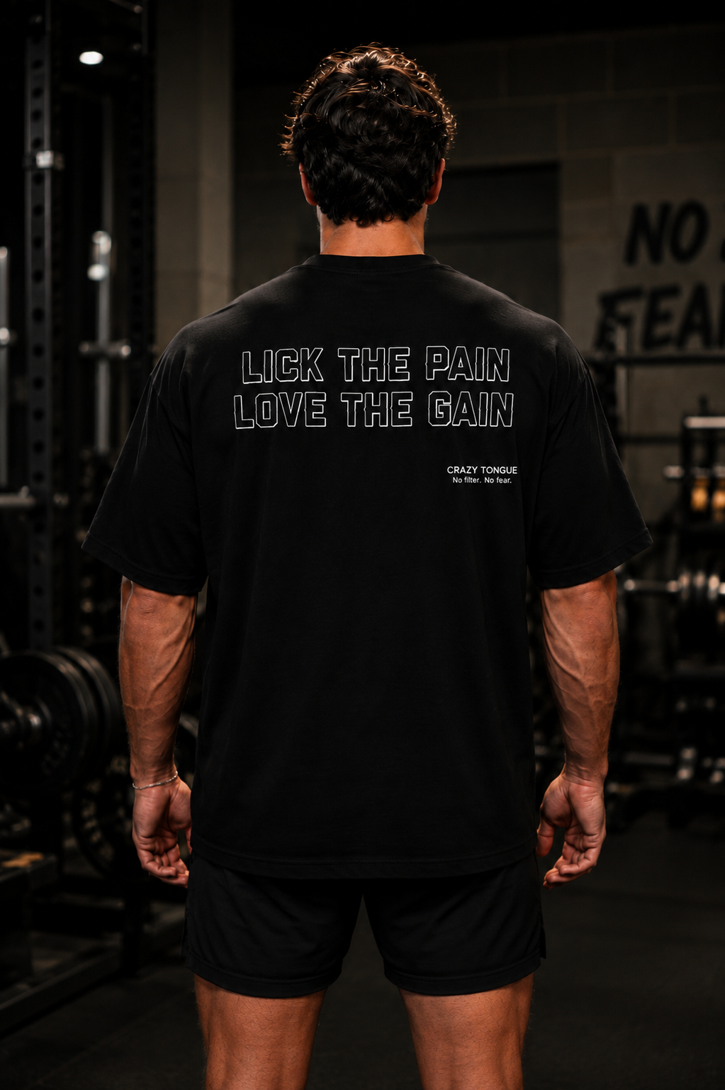 Homme portant le t-shirt noir Crazy Tongue LICK PAIN de dos dans une salle de sport.