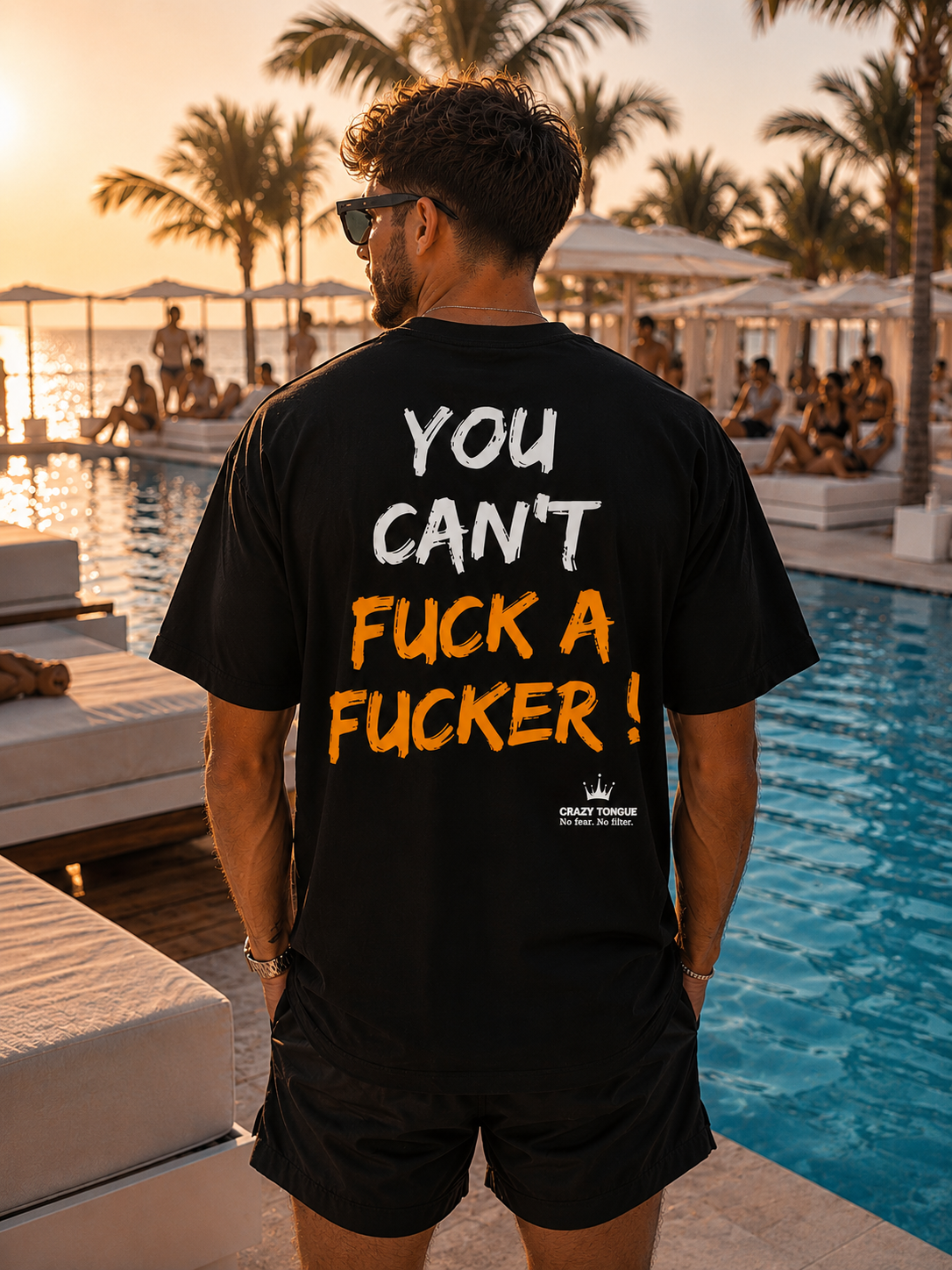 Homme portant le t-shirt noir Crazy Tongue HARD TO HANDLE de dos, artwork orange, au bord d'une piscine au coucher du soleil.