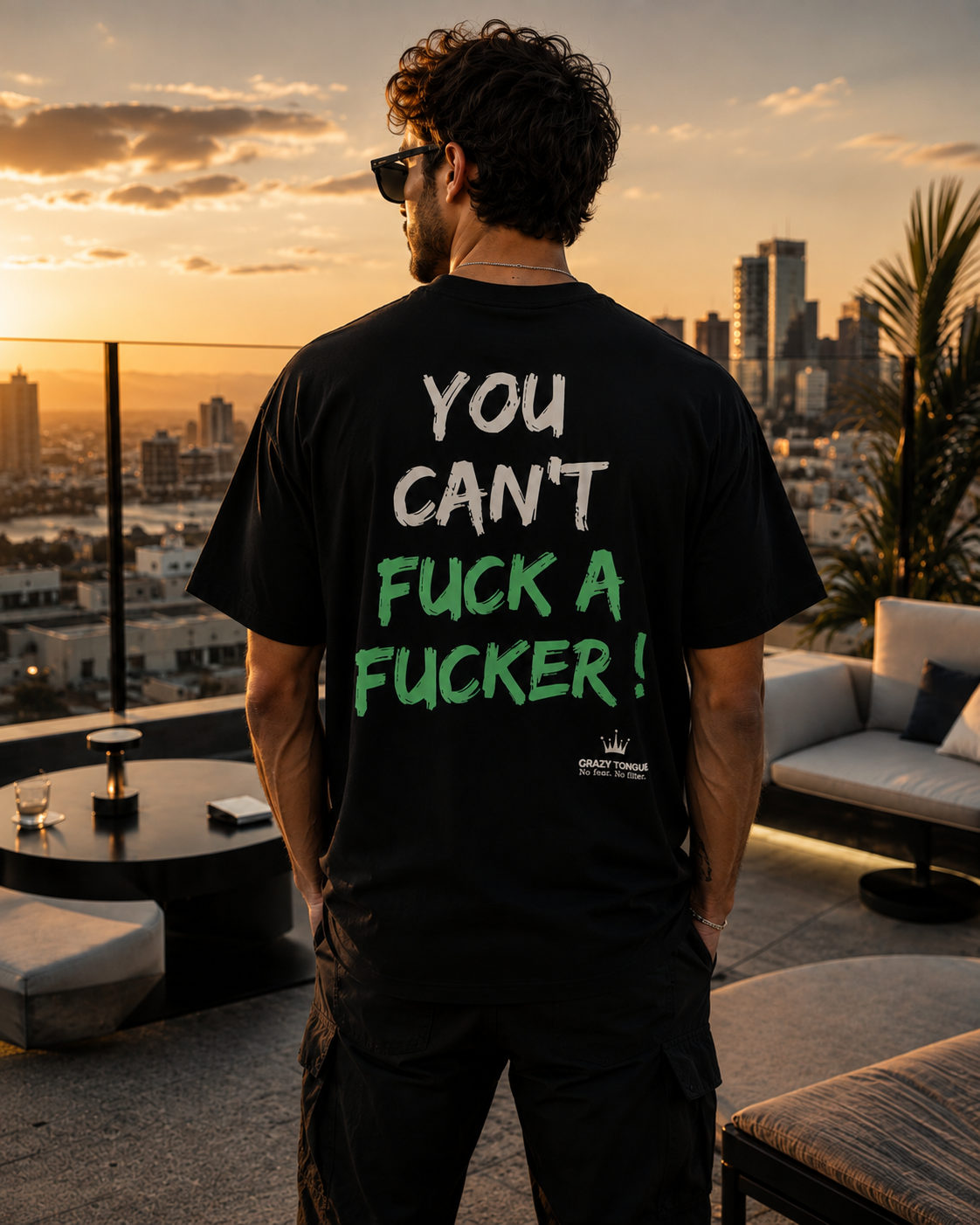 Homme portant le t-shirt noir Crazy Tongue HARD TO HANDLE de dos, artwork vert, sur un rooftop au coucher du soleil.